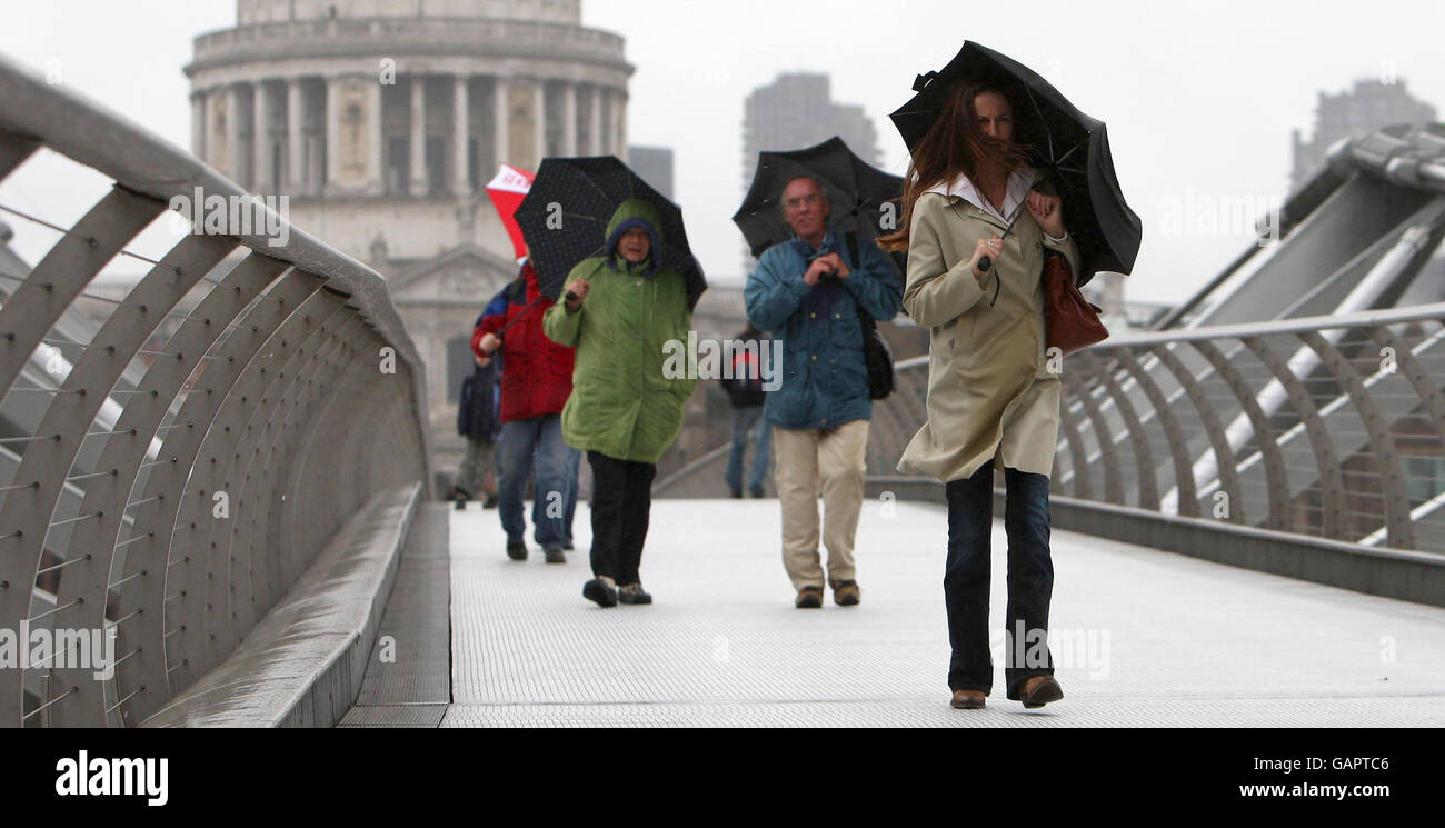 Die Menschen kämpfen durch starke Winde und Regen, wenn sie die Millennium Bridge in London überqueren. Stockfoto