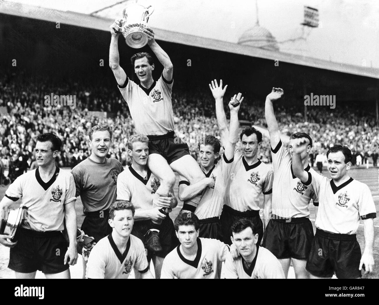 Wolverhampton Wanderers Kapitän Bill Slater hält den FA Cup hoch, während er von seinen jubelnd Teamkollegen geleitet wird: (Hintere Reihe, l-r) Gerry Harris, Malcolm Finlayson, Ron Flowers, Peter Broadbent, Eddie Clamp, George Showell, Norman Deeley; (vordere Reihe, l-r) Barry Stobart, des Horne, Jimmy Murray Stockfoto