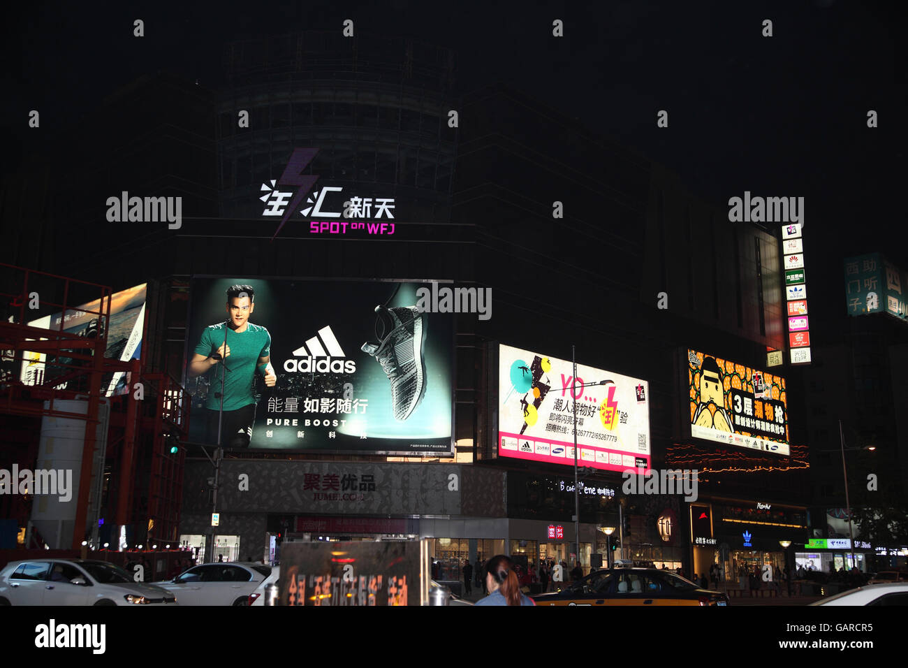 Abend, riesige Plakate Werbung europäischen und chinesischen Unternehmen an der Kreuzung von Donganmen und Wangfujing Street, Beijing Nachtleben, China. Stockfoto