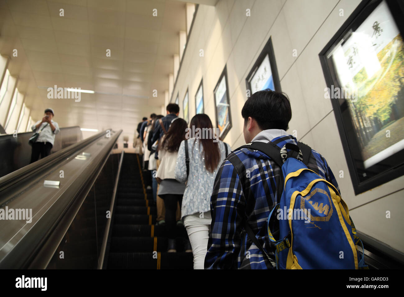 In den frühen Morgenstunden verwenden junge Chinesen eine Rolltreppe, verlassen Sie die u-Bahn an der Chedaogou Station.  Peking, China. 26.04.2016. Stockfoto