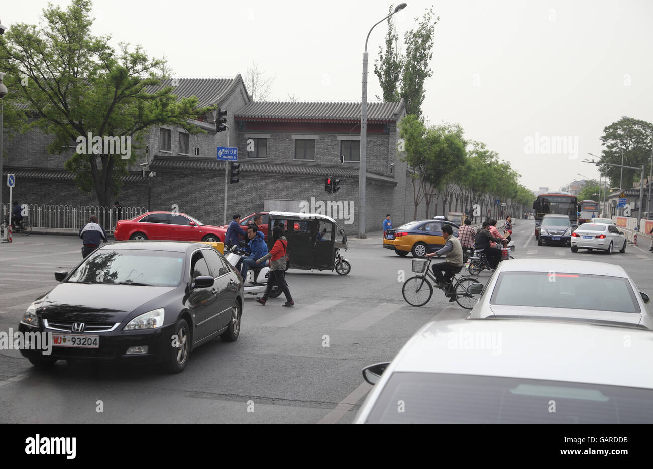 Roller, Dreirad Lastwagen, Fahrräder und Fußgänger überqueren Sie die Kreuzung gehen alle durch Autos, Reisen, zu drehen oder zu stoppen. Peking, China. Stockfoto