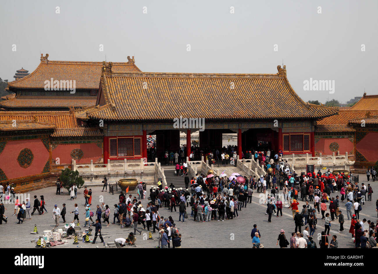 Touristen besuchen das Tor der Himmlischen Reinheit in der verbotenen Stadt, dazwischen Arbeiter die Boden-Fliesen reparieren. Peking, China. Stockfoto