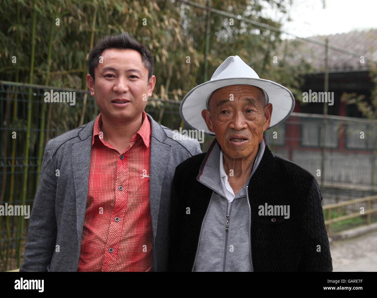 Eine ehrliche Porträt von zwei chinesischen Männern, ein Großvater mit einem Hut und sein Enkel. Der Sommerpalast, Peking, China. Stockfoto