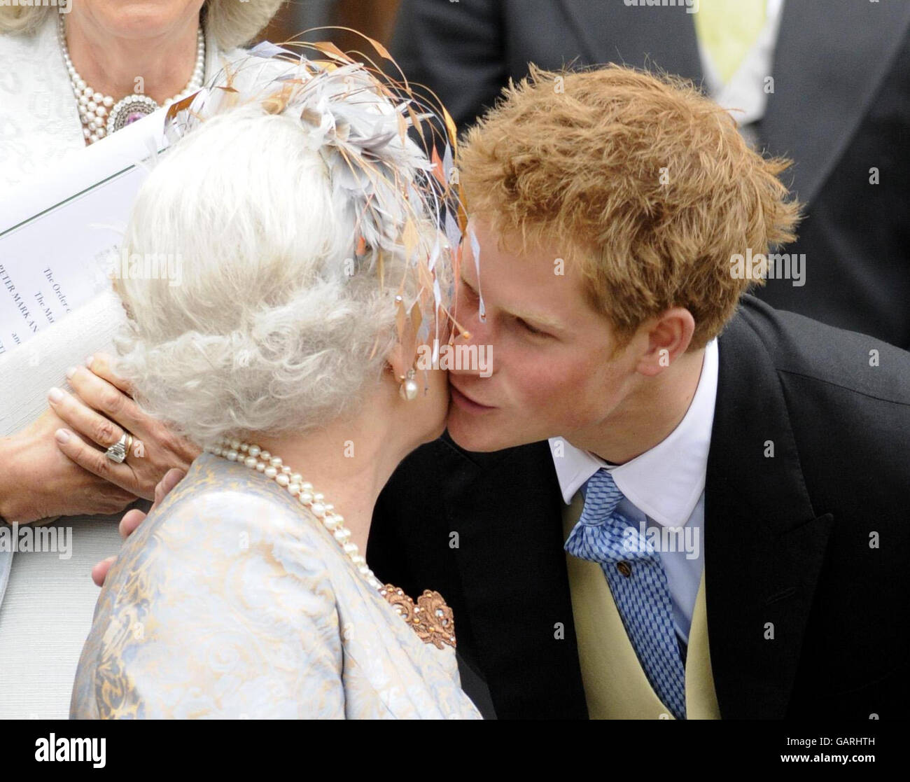 Prinz Harry gibt seiner Großmutter, Königin Elizabeth II., nach der Hochzeit von Peter Phillips und Autumn Kelly einen Kuss vor der St. George's Chapel in Windsor. Stockfoto