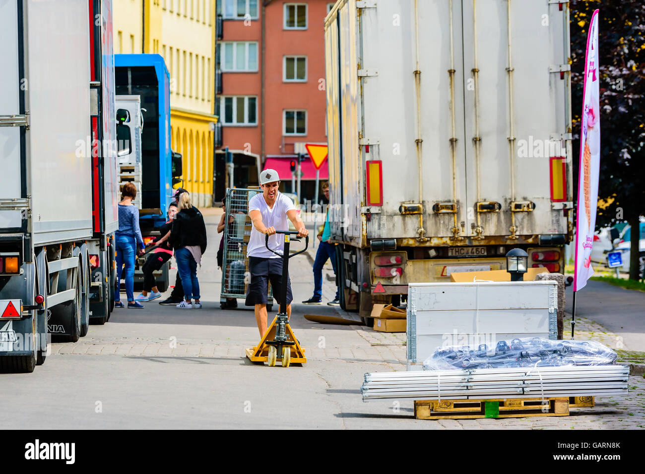 Motala, Schweden - 21. Juni 2016: Junge Männchen mit einem Hubwagen, um ihm gegenüber eine Kiste zu transportieren, das geladen werden soll ein Stockfoto