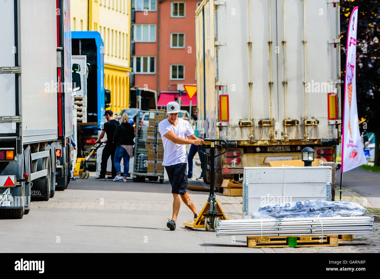 Motala, Schweden - 21. Juni 2016: Junge Männchen mit einem Hubwagen, um ihm gegenüber eine Kiste zu transportieren, das geladen werden soll ein Stockfoto
