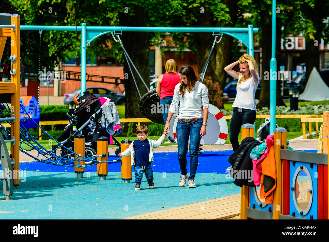 Motala, Schweden - 21. Juni 2016: Junge Erwachsene Frau zu Fuß mit einem kleinen Jungen auf dem Spielplatz. Vielleicht Mutter und Sohn. Anderen pe Stockfoto