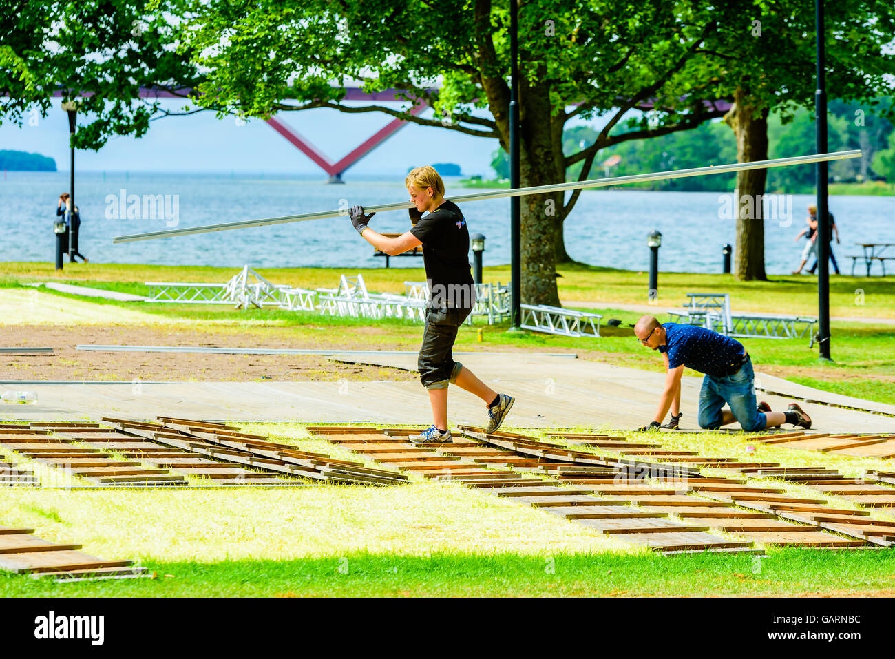 Motala, Schweden - 21. Juni 2016: Junge erwachsene Arbeitnehmer Aufräumarbeiten nach einem Ereignis in den Park. Eine Person mit langen Planken über Stockfoto