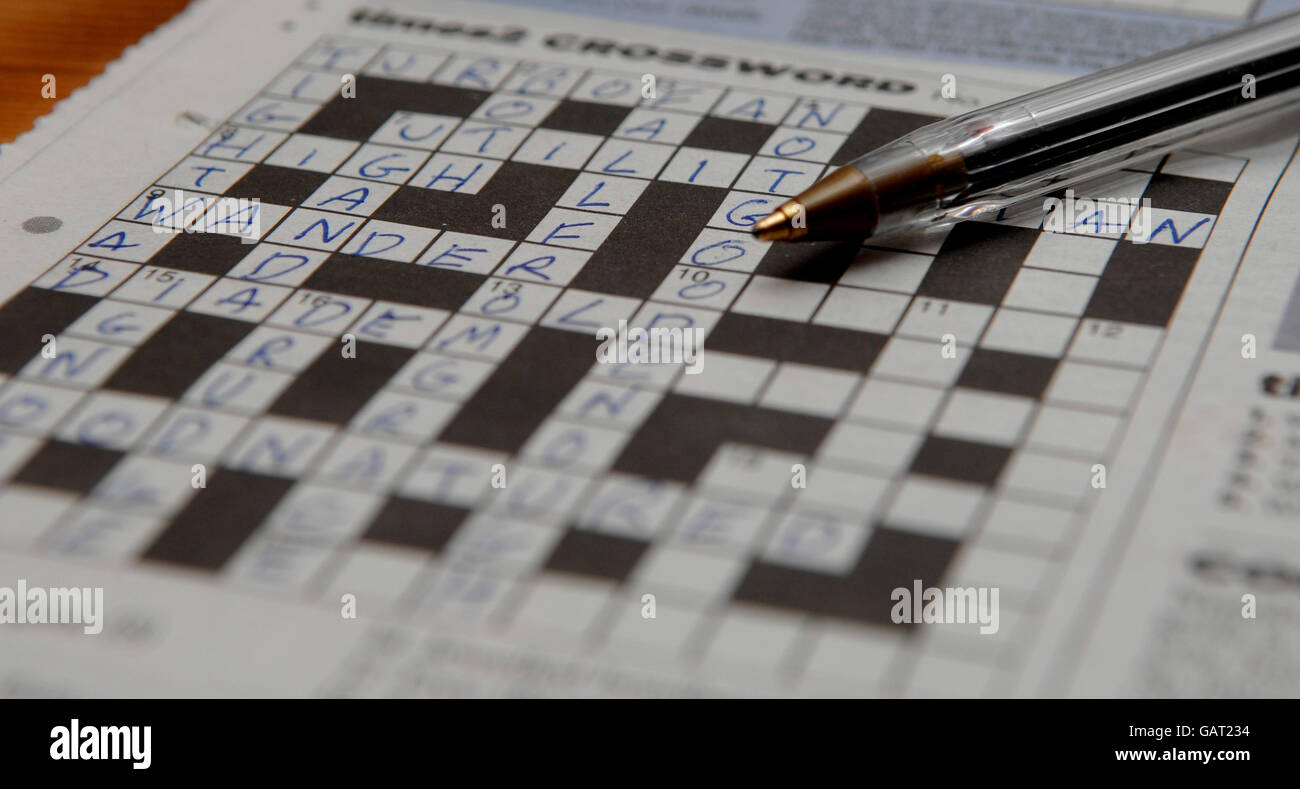 Generisches Foto eines Kreuzworträtsels, das zur Hälfte mit einem Kugelschreiber fertig ist, der auf dem Puzzle ruht. Stockfoto