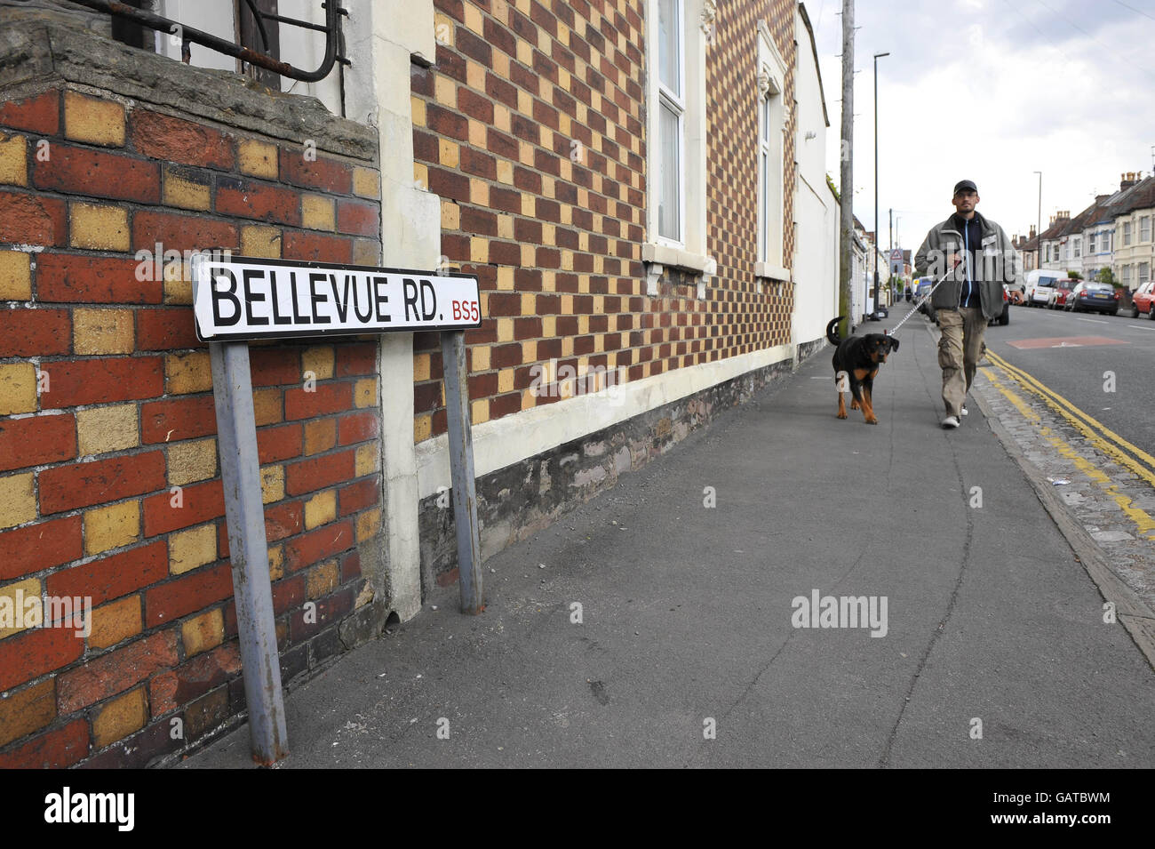 Ein Mann geht mit seinem Hund in der Belle Vue Road, Easton, Bristol, als die Polizei ein Grundstück auf der Straße durchsucht, nachdem ein 19-jähriger Mann nach dem Terrorismusgesetz in der Stadt verhaftet wurde. Stockfoto