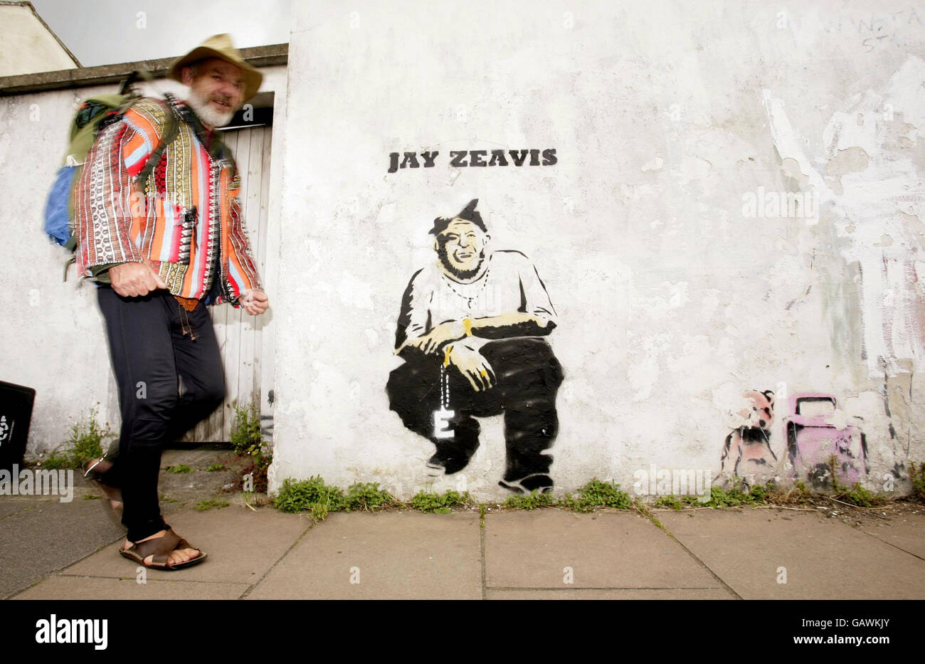 Ein Festivalbesucher bewundert ein Graffiti von Banksy, das den Veranstalter des Glastonbury Festivals Michael Eavis als Festivalheadliner Jay-Z im Stadtzentrum von Glastonbury am Vorabend des Festivals zeigt. Stockfoto