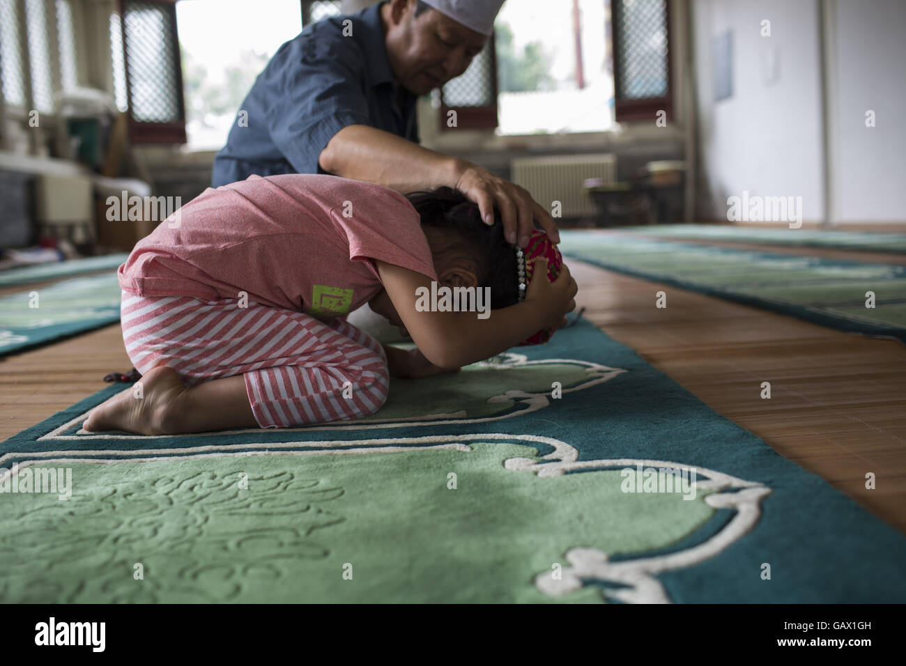Peking, China. 6. Juli 2016. Großvater seiner Enkelin beibringen zu beten. Muslime auf der ganzen Welt feiern das religiöse Fest Eid al-Fitr, die signalisiert das Ende des heiligen Fastenmonats Ramadan. Niujie Moschee ist die älteste Moschee in Peking und im 996 n. Chr. erbaut wurde. Bildnachweis: Jiwei Han/ZUMA Draht/Alamy Live-Nachrichten Stockfoto