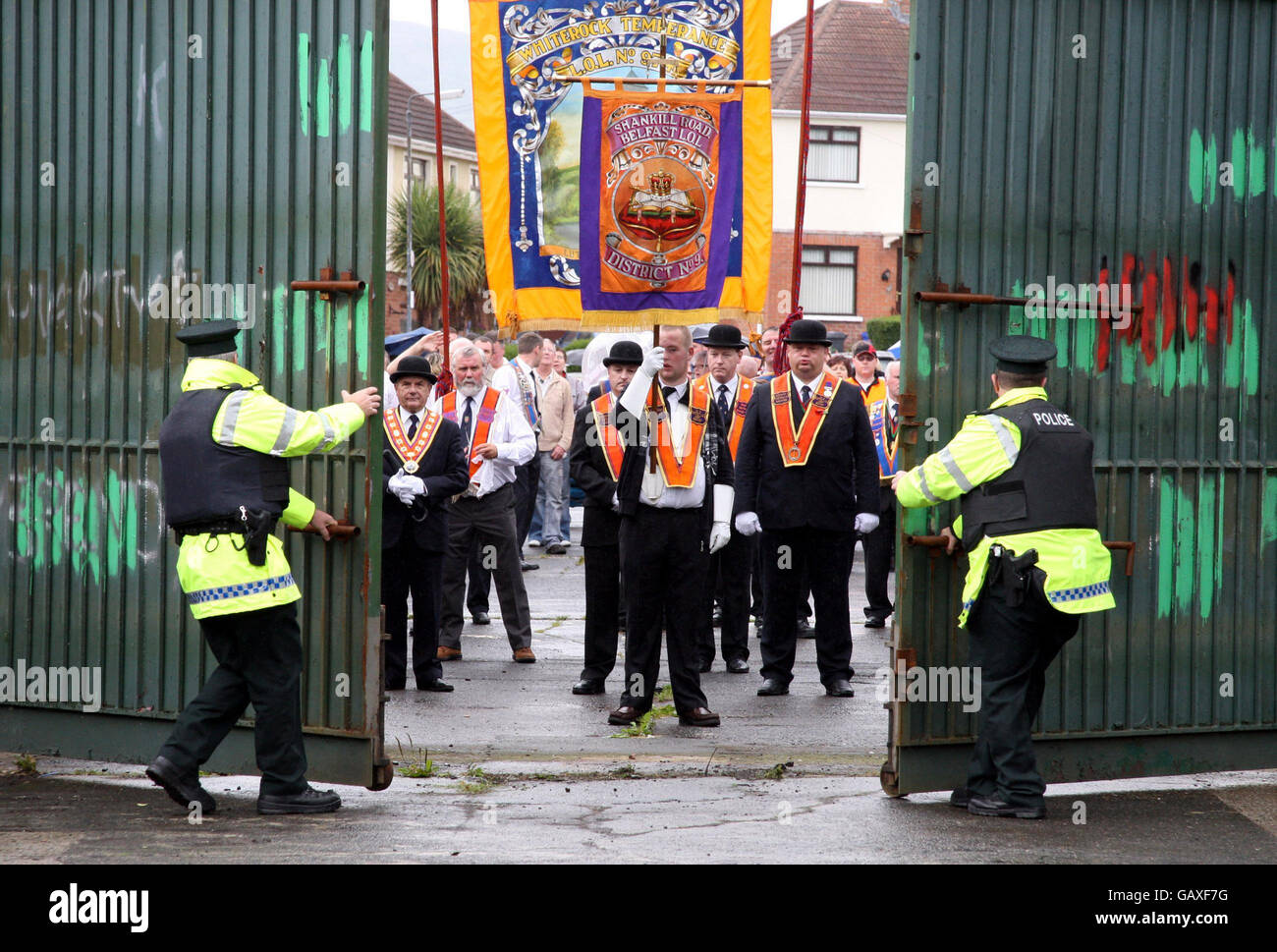Polizeibeamte des nordirischen Polizeidienstes öffnen in der Workman Avenue im Westen von Belfast, Nordirland, das Tor für den Orange Order. Stockfoto