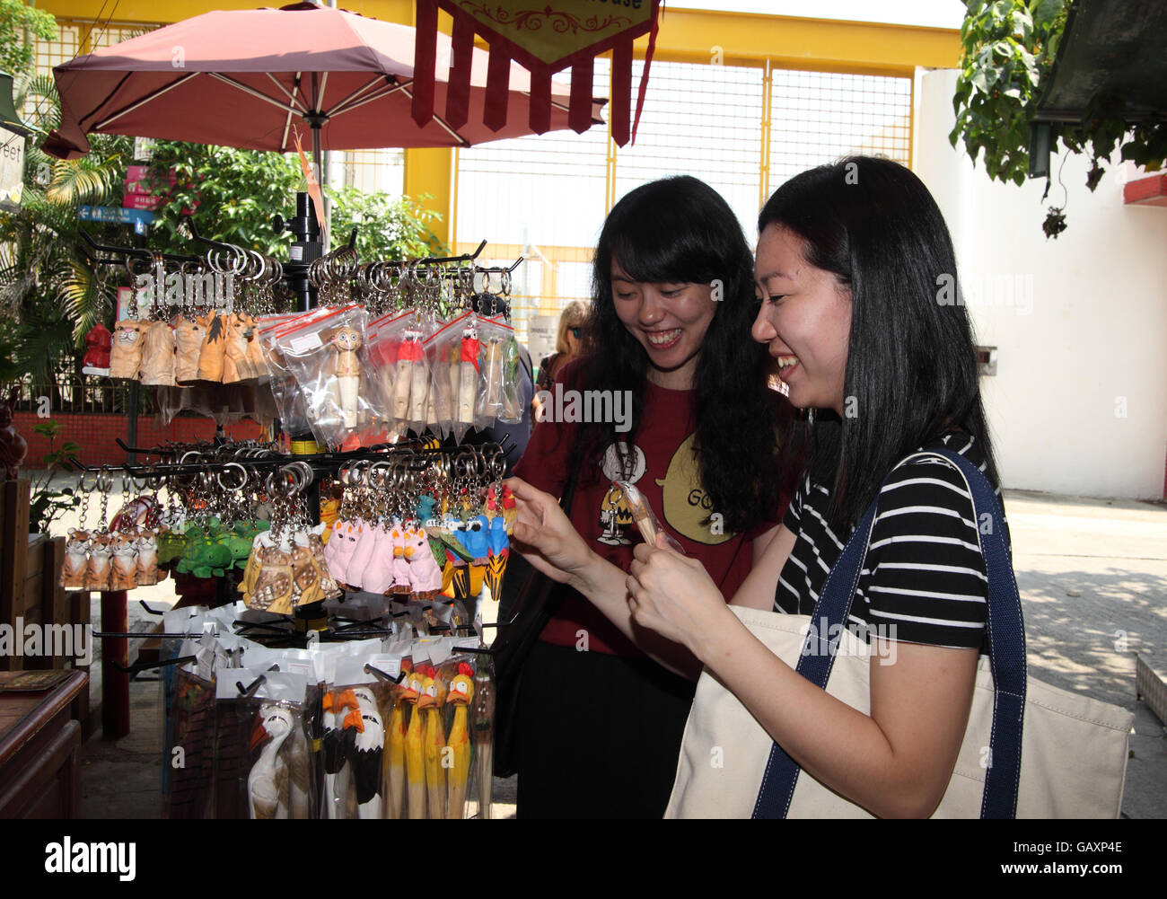 Zwei junge chinesische Frauen Lächeln wenn sie Souvenirs im Shop auf dem Stanley Market betrachten. Stanley Village, Hong Kong. 06.05.2016. Stockfoto