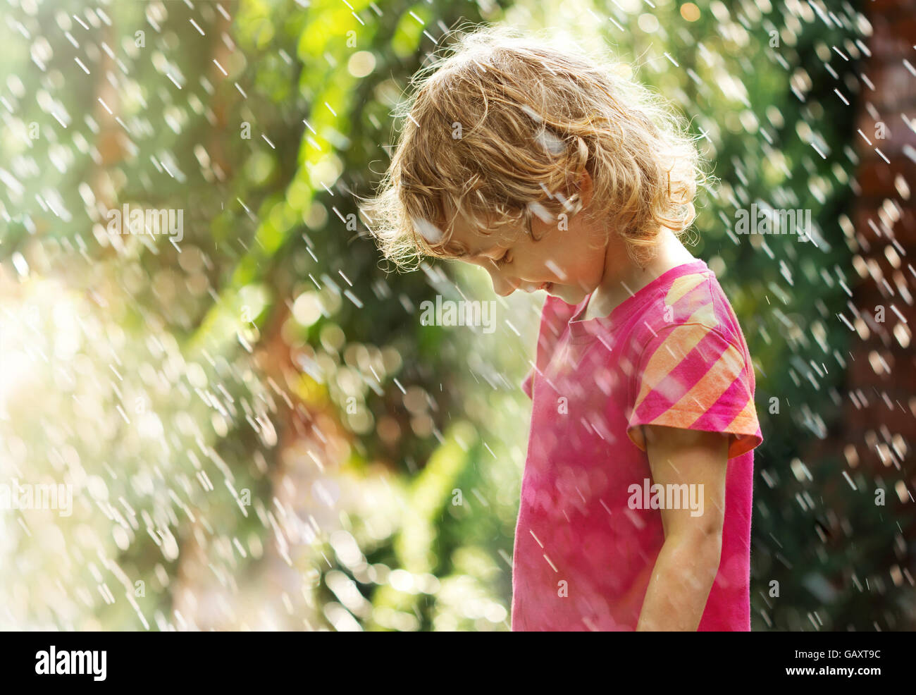 Foto von glückliche kleine Mädchen stehen unter Sommerregen Stockfoto