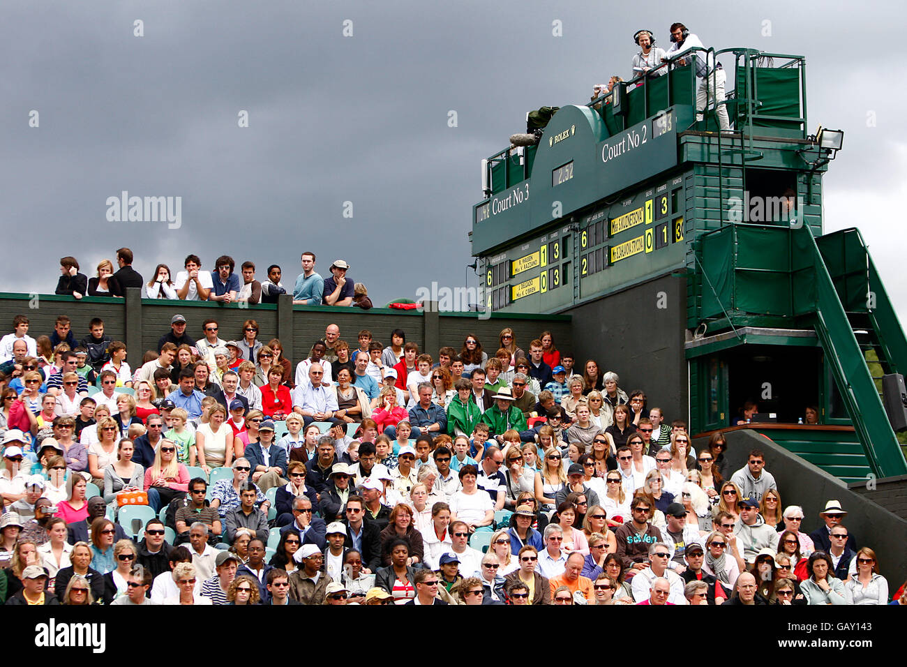 Tennis - Wimbledon Championships 2008 - Tag Fünf - The All England Club. Die Zuschauer auf dem Platz Nr. 2 beobachten das Geschehen am 5. Tag von Wimbldon, während sich hinter ihnen Sturmwolken versammeln Stockfoto