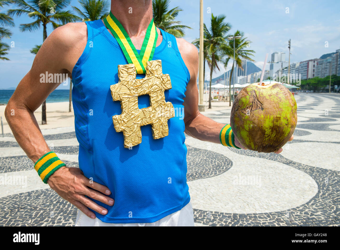 Athlet mit Hashtag Goldmedaille Stand mit Coco Gelado trinken Kokosnuss auf den gemusterten Fliesen von der Promenade am Copacabana Stockfoto