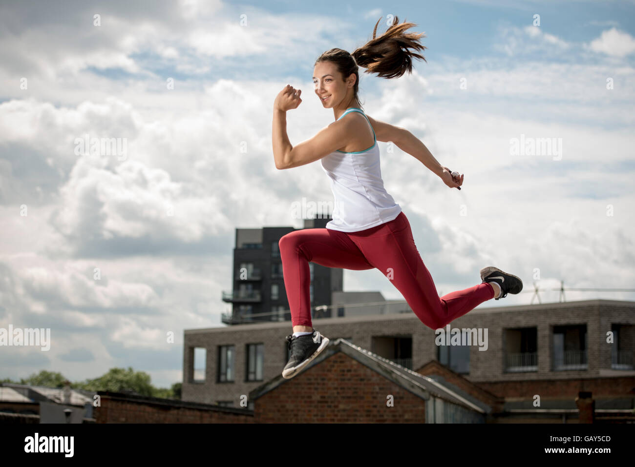 Sportliche Frau trägt Fitness tragen in die Luft springen Stockfoto