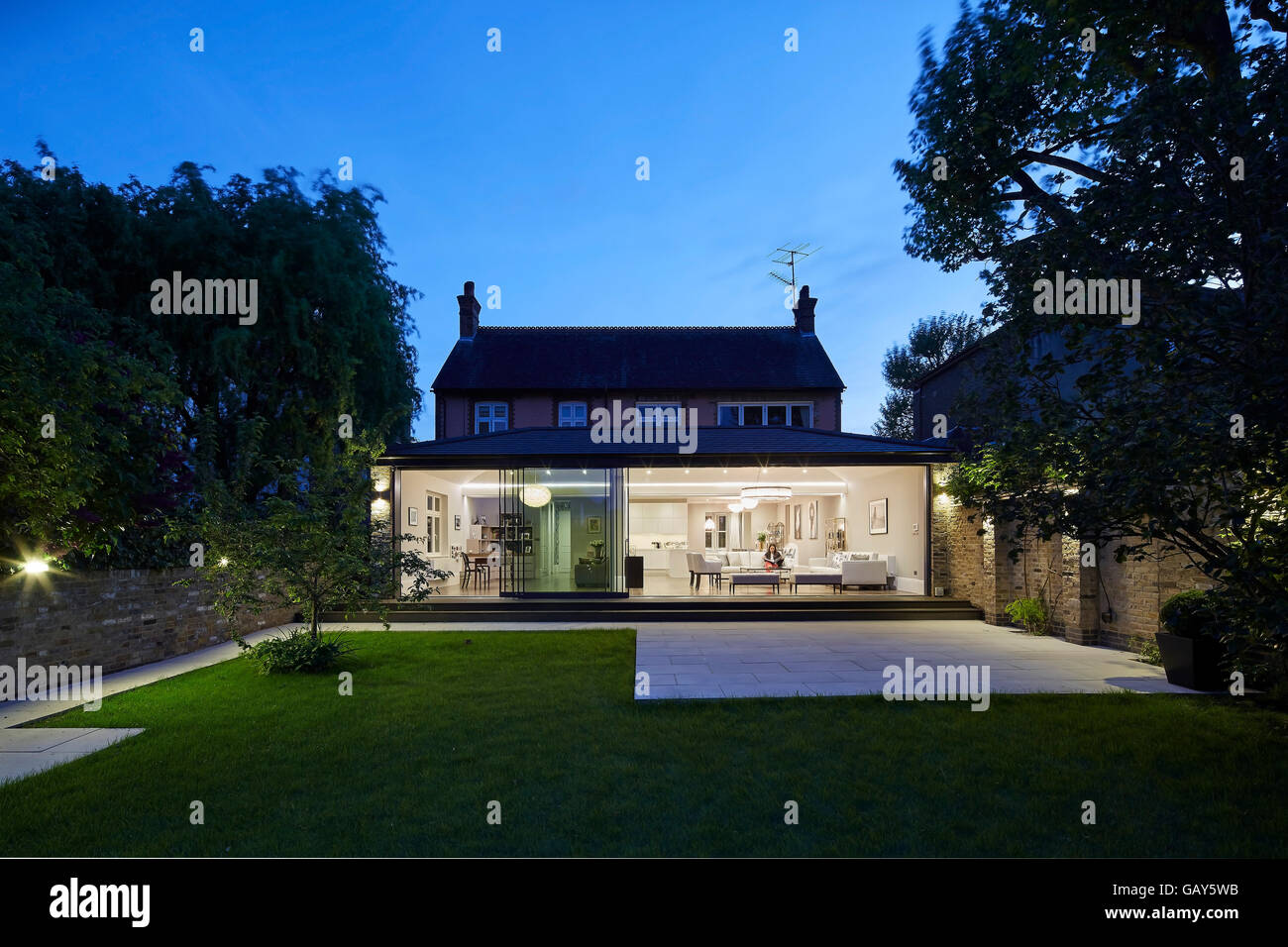 Twilight-Blick vom Garten in Richtung beleuchtet Erweiterung Innenraum. Privathaus, Highlever Road, London, Vereinigtes Königreich. Architekt: Sophie Nguyen Architekten, 2015. Stockfoto