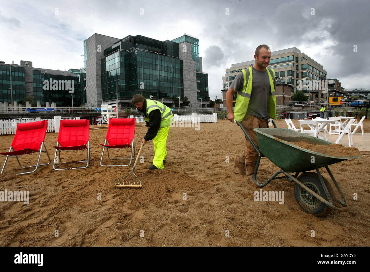 Arbeiter bereiten den von Mini cooper gesponserten Urban Beach im IFSC Dublin vor, trotz heftiger Regenfälle, die morgen eröffnet werden sollen. Stockfoto