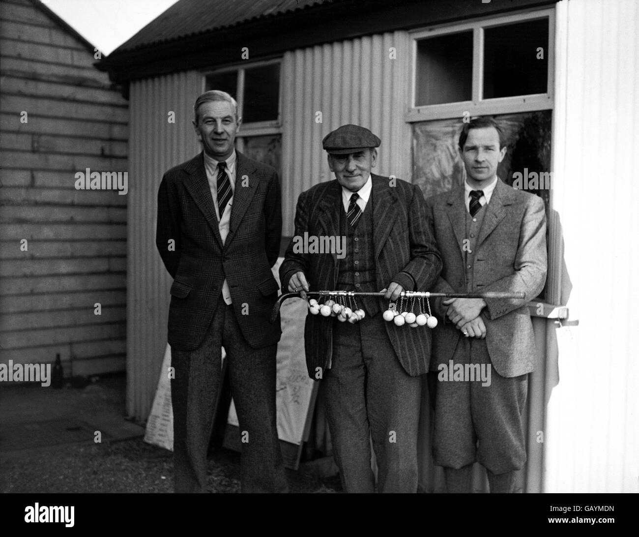 Bernard Darwin (c) wird von dem Gewinner des Turniers, PB Lucas (r), und dem Vizemeister, Roger Wethered (l), flankiert, während er den Putter des Präsidenten schwingt Stockfoto