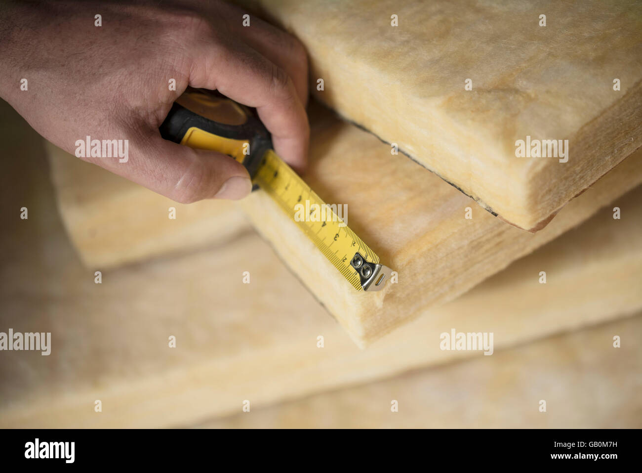 Hand, die Messung einer Fiberglas-Batt. Bild der Hausdämmung. Stockfoto