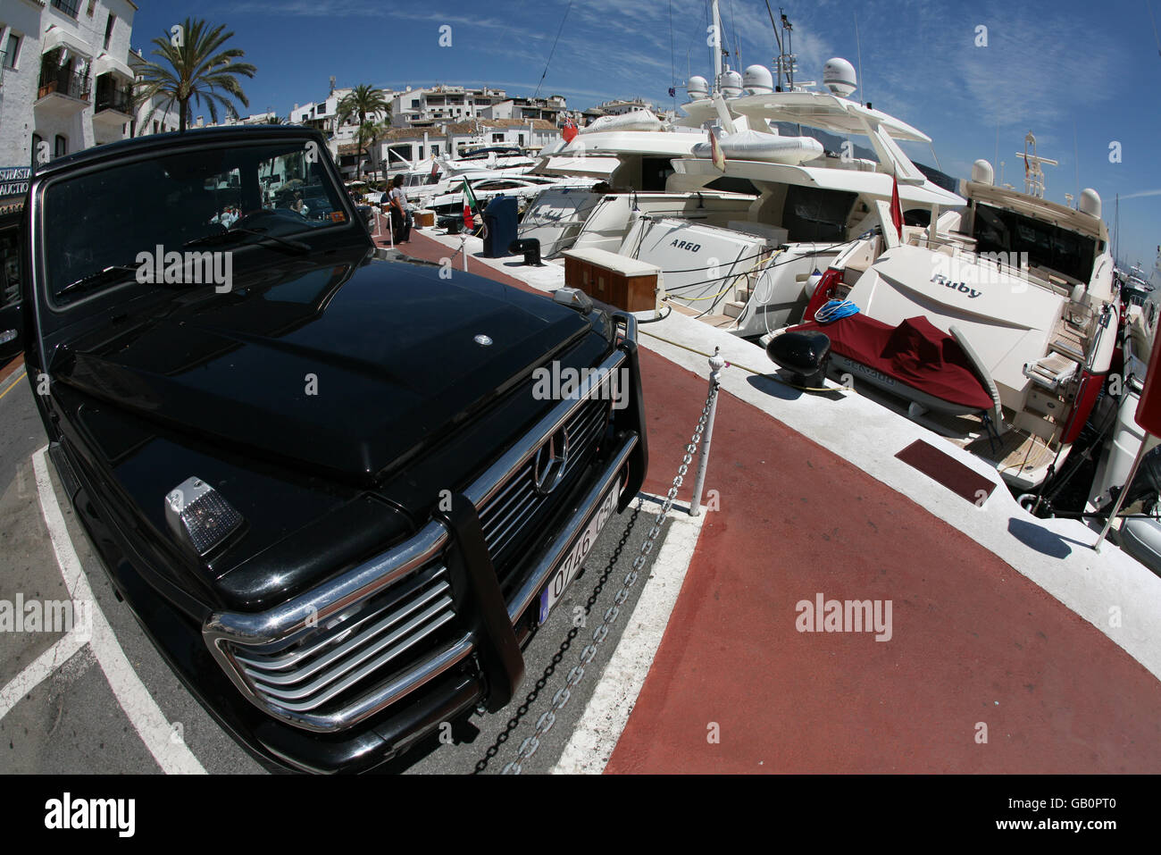 Ein Mercedes-Fahrzeug neben Superyachten in Puerto Banus. Stockfoto