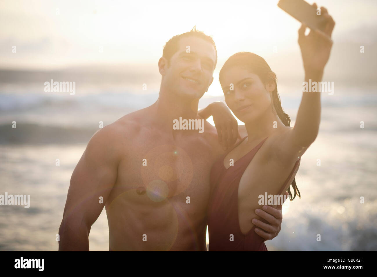 Junger attraktiver Mann und Frau sind Selfie am Strand bei Sonnenuntergang fotografieren Stockfoto