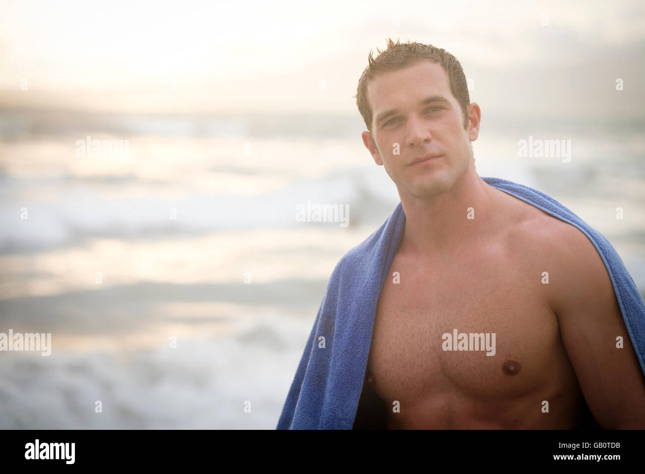 Porträt des jungen muskulösen Mann mit Tuch auf seinen Schultern an einem Strand Stockfoto