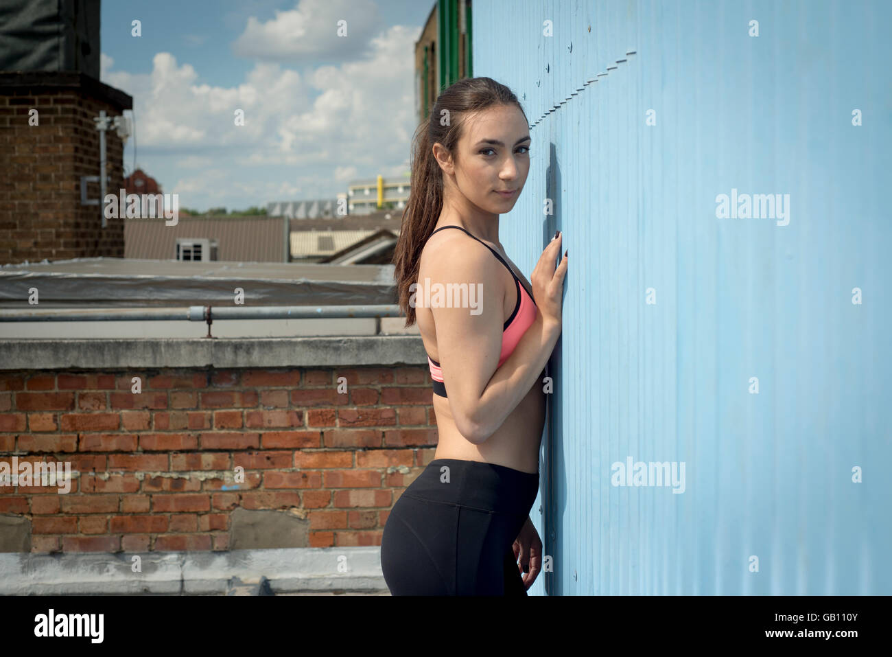 Sportliche Frau trägt Fitness tragen Wand gelehnt Stockfoto