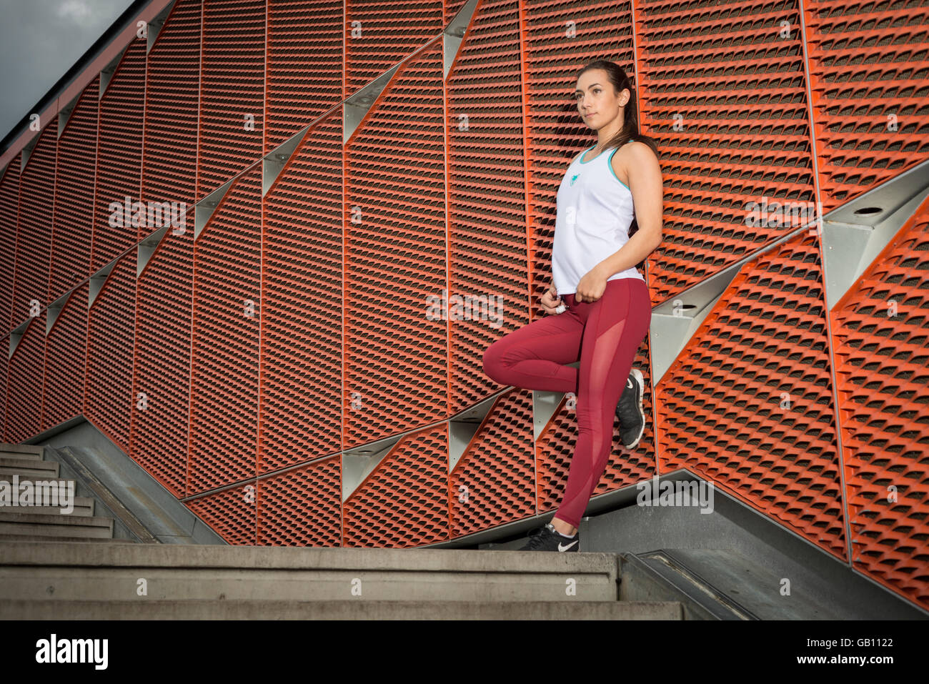 Sportliche Frau trägt Fitness tragen eine Wand gelehnt Stockfoto