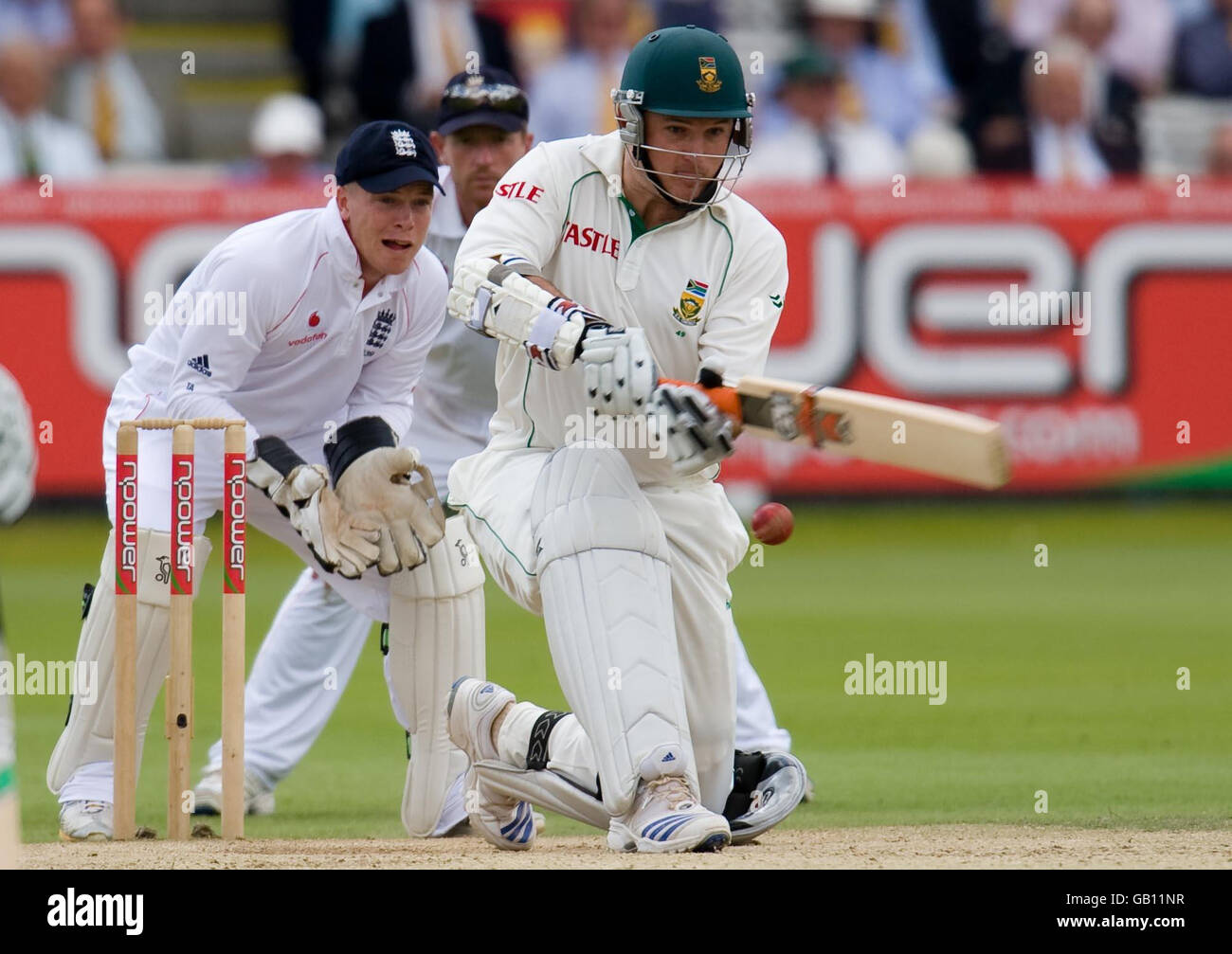 Der südafrikanische Kapitän Graeme Smith fegt den Ball, während er vom englischen Wicketkeeper Tim Ambrose während des ersten npower-Test-Spiels auf dem Lord's Cricket Ground in London beobachtet wird. Stockfoto