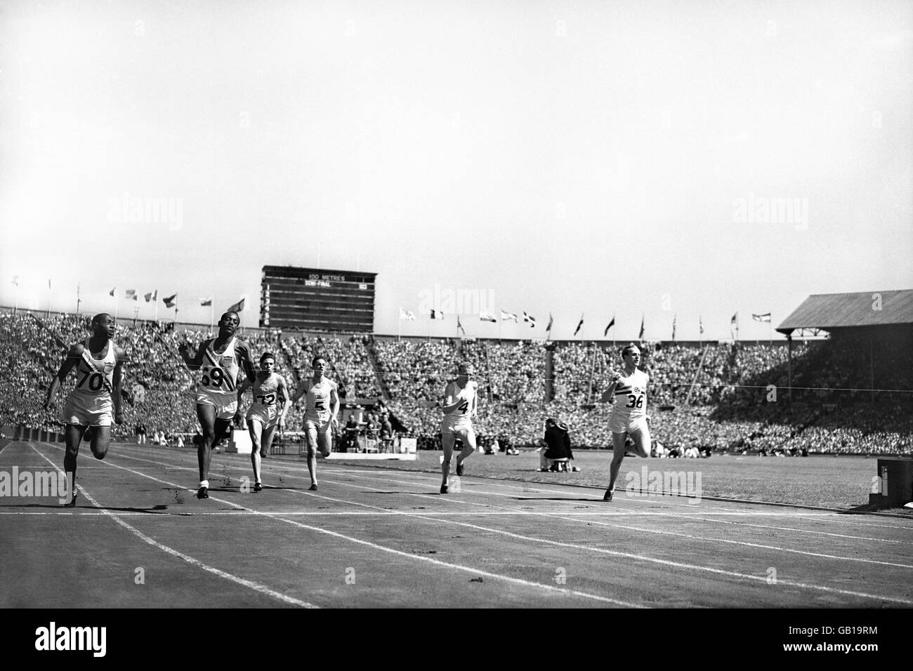 Der US-Amerikaner Harrison Dillard (zweiter Rang) bricht das Band und gewinnt mit seinem Teamkollegen Barney Ewell (zweiter Rang), dem britischen Alastair McCorquodale (zweiter Rang), dem australischen John Bartram (zweiter Rang), dem australischen Morris Curotta (dritter Rang) und dem Uruguays JJ Testea Lopez (dritter Rang) Stockfoto