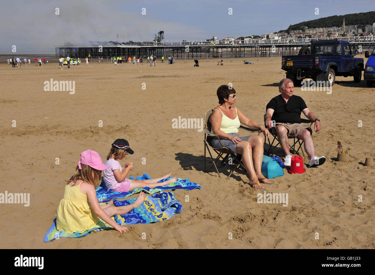 Weston-super-Mare Pier Feuer. Touristen genießen die Sonne am Strand am Grand Pier in Weston-super-Mare, nachdem ein Großbrand ausbrach. Stockfoto