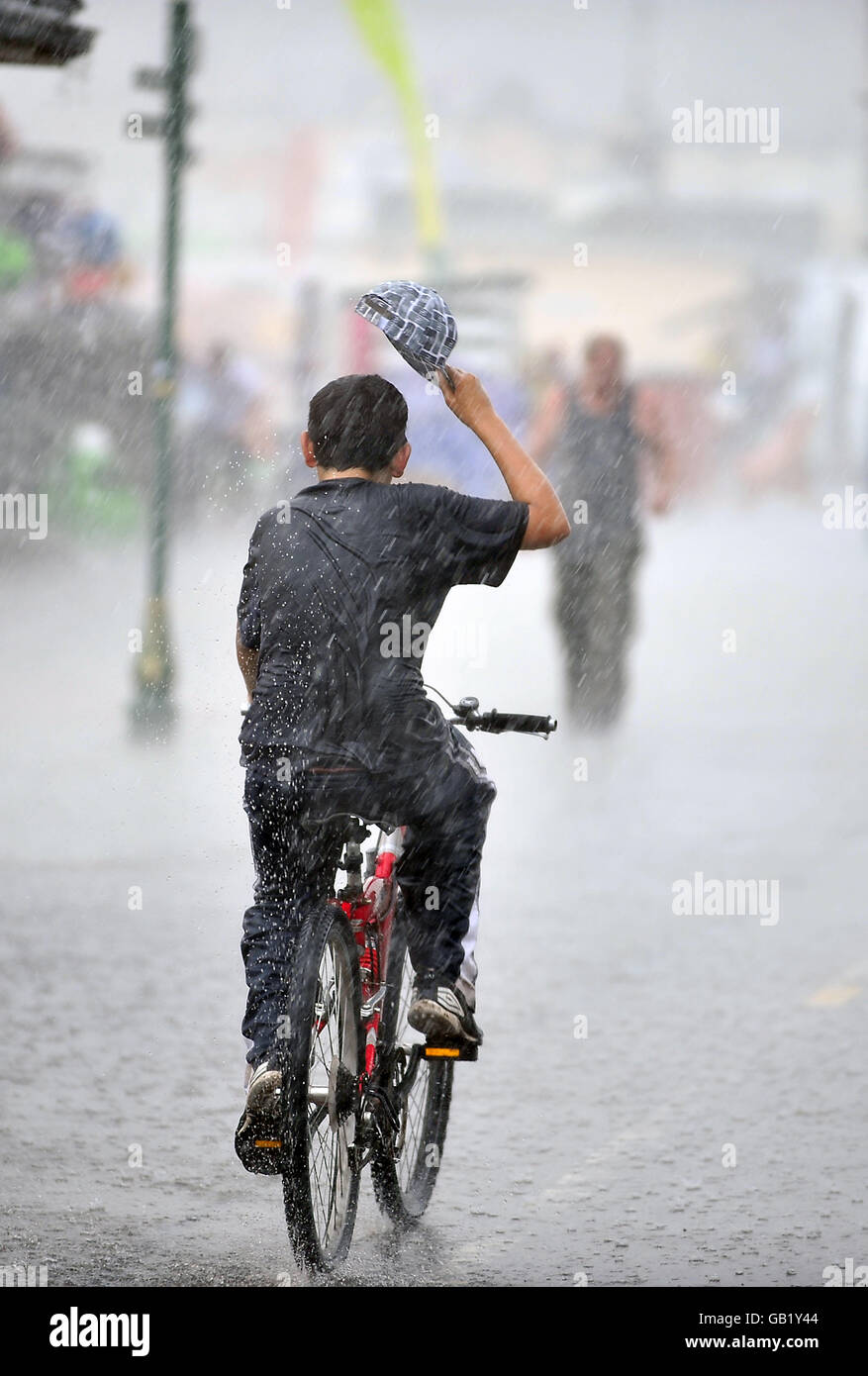 Ein Radfahrer ist in einem kurzen Sommerregen auf der Promenade bei Weston-super-Mare gefangen. Stockfoto