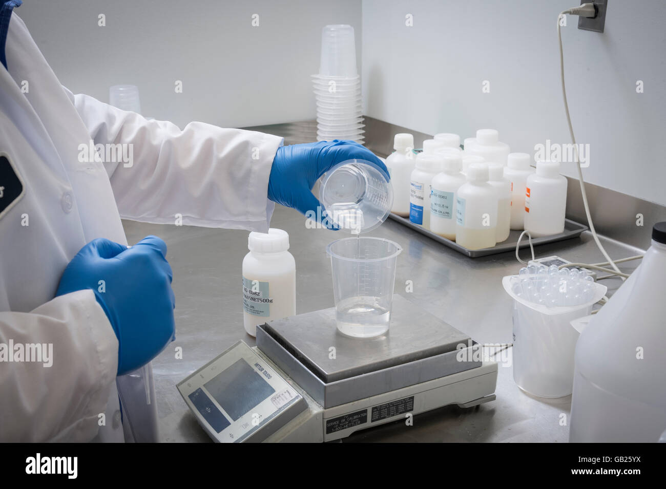 Lab Technician übergibt strömende Chemikalien im Becher zum Wiegen Messung Stockfoto