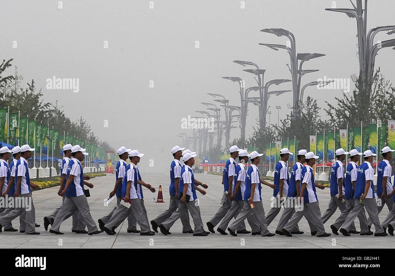 Die Freiwilligen der Olympischen Spiele von Peking marschieren heute auf ihre Positionen über die Hauptzuschauallee, die zum Nationalstadion führt, mit dem Dunst und der Verschmutzung, die in Peking vor der Eröffnungszeremonie morgen wieder vorhanden sind. Stockfoto