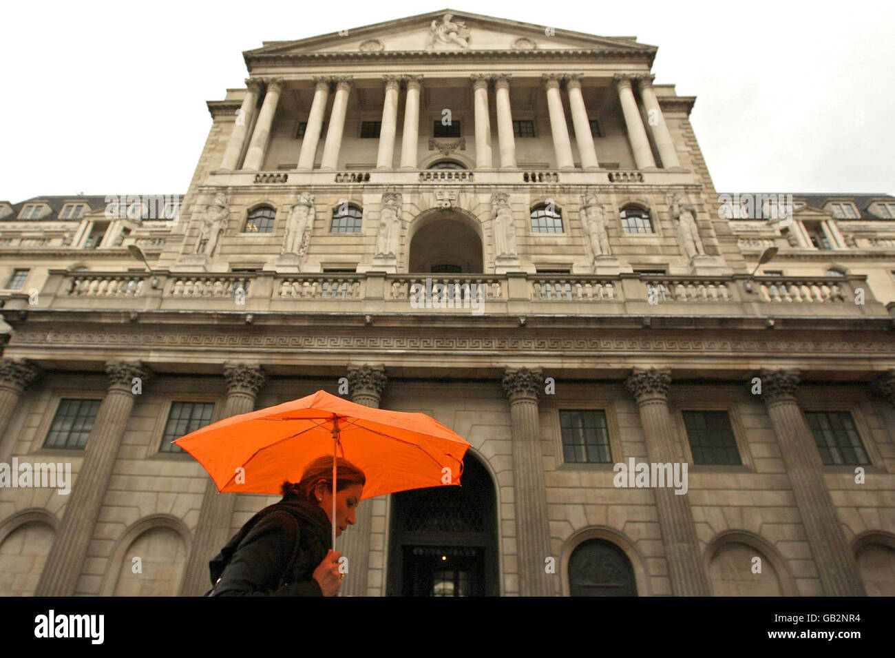 Warnung der Bank of England. Eine Frau untersteht einem Regenschirm, als sie an der Bank of England, London, vorbeigeht. Stockfoto
