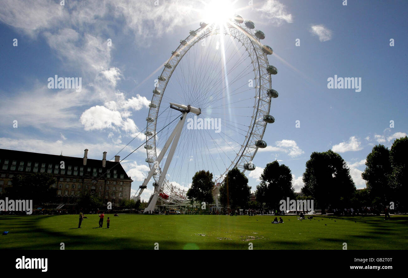 Die Menschen passieren das London Eye am South Bank, während die Londoner das sonnige Wetter genießen. Stockfoto