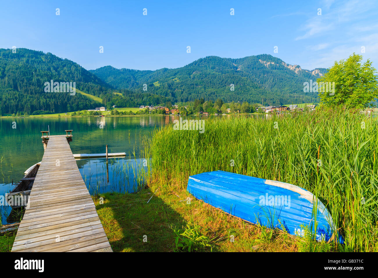 Holzsteg und blau Boot am Ufer des Weissensee Alpensee in Sommerlandschaft, Österreich Stockfoto
