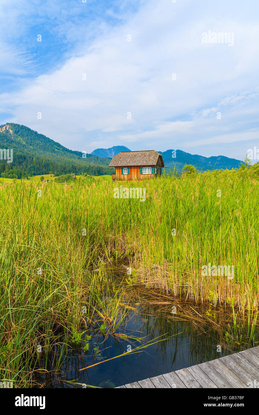 Hölzerne Pier am Ufer des Weißensee und typische alpine House in Ferne im Sommerlandschaft der Alpen, Österreich Stockfoto