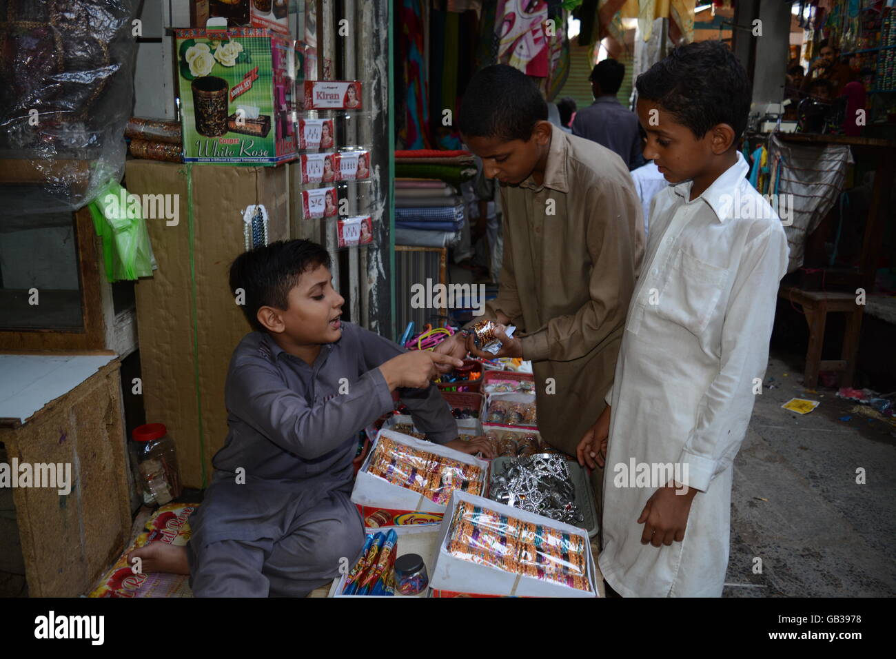 10 Jahre alter Junge verkaufen verschiedene Artikel für den Einsatz beim Sitzen vor einem Geschäft im Hauptmarkt Stockfoto