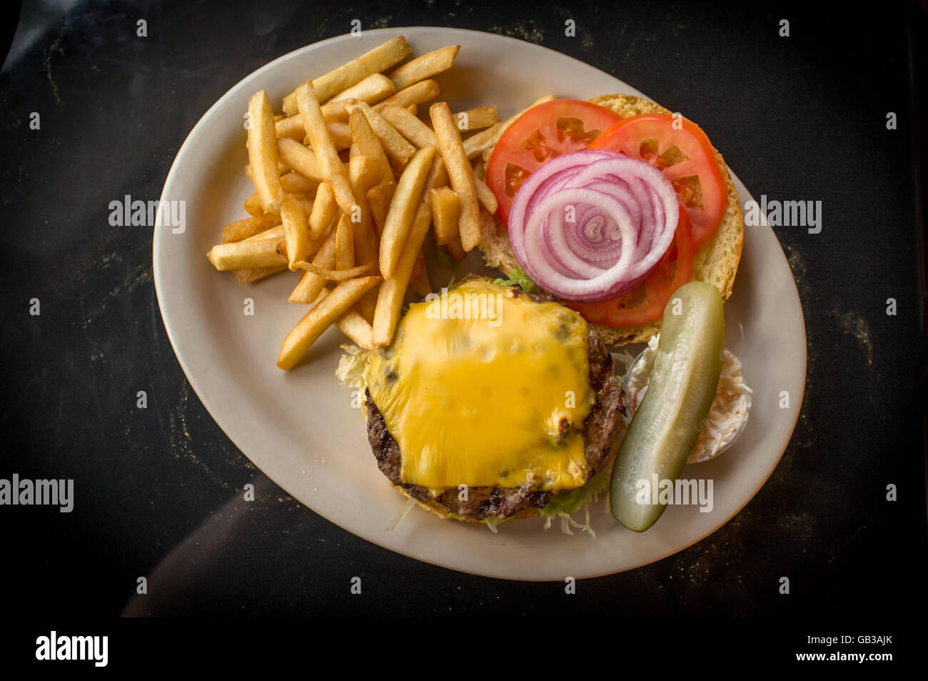 Cheeseburger auf einem Vollkorn-Brötchen mit Steak Pommes Frites auf der Seite Stockfoto