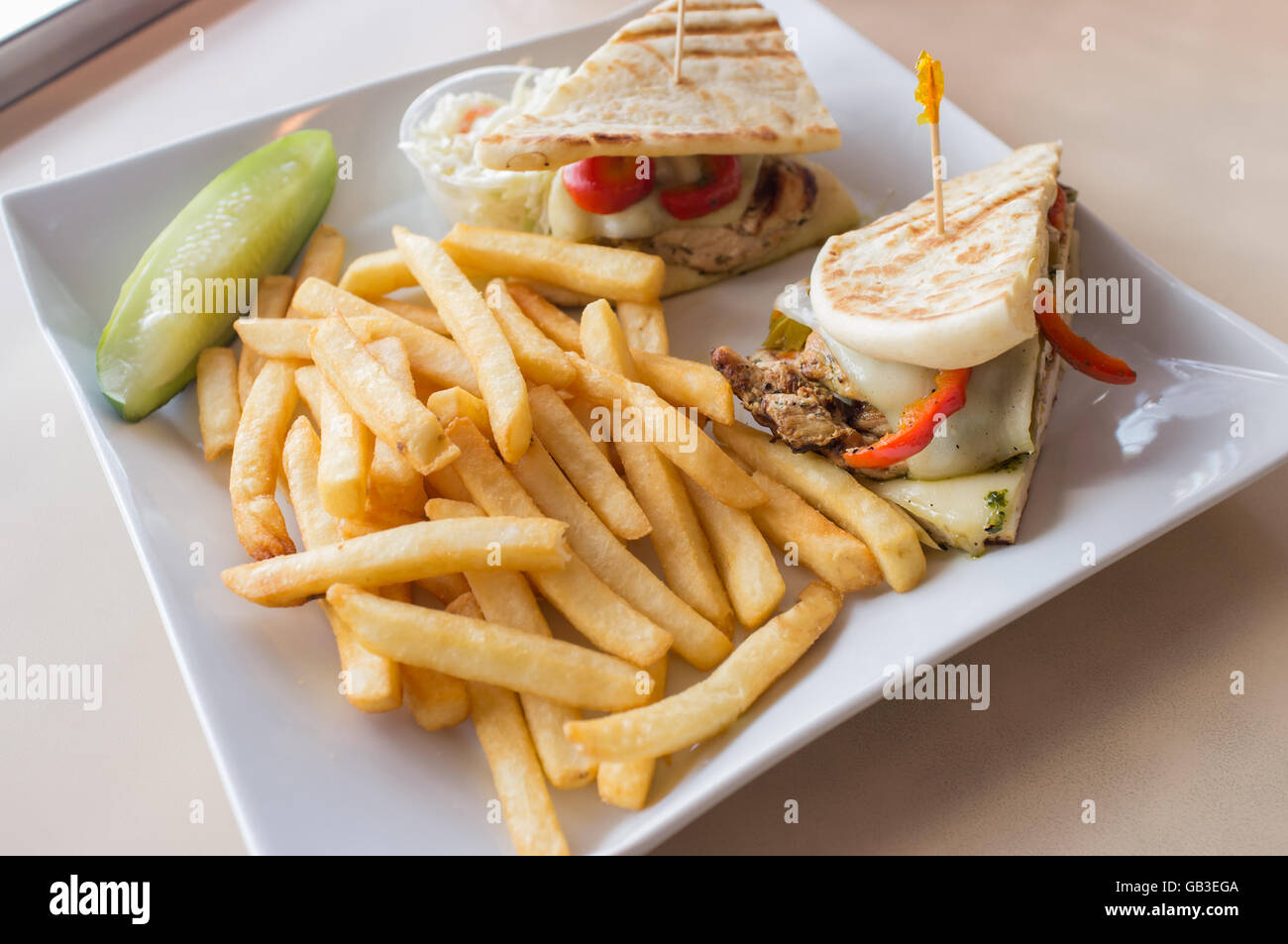 Gegrillten Pesto chicken Panini mit knusprigen Steak frites Cole Slaw und Gurke Stockfoto