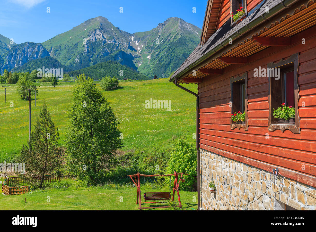 Holzhaus auf der grünen Wiese mit Tatry Bielskie Berge im Hintergrund im Sommer, Slowakei Stockfoto