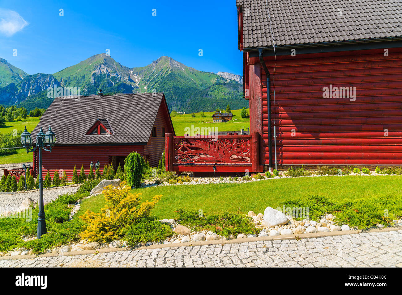 Holzhäuser auf grüner Wiese mit Tatry Bielskie Bergen im Hintergrund im Sommer, Slowakei Stockfoto