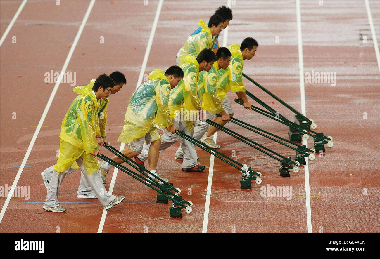 Freiwillige schwammen Regenwasser von der Strecke im Nationalstadion in Peking, China. Stockfoto