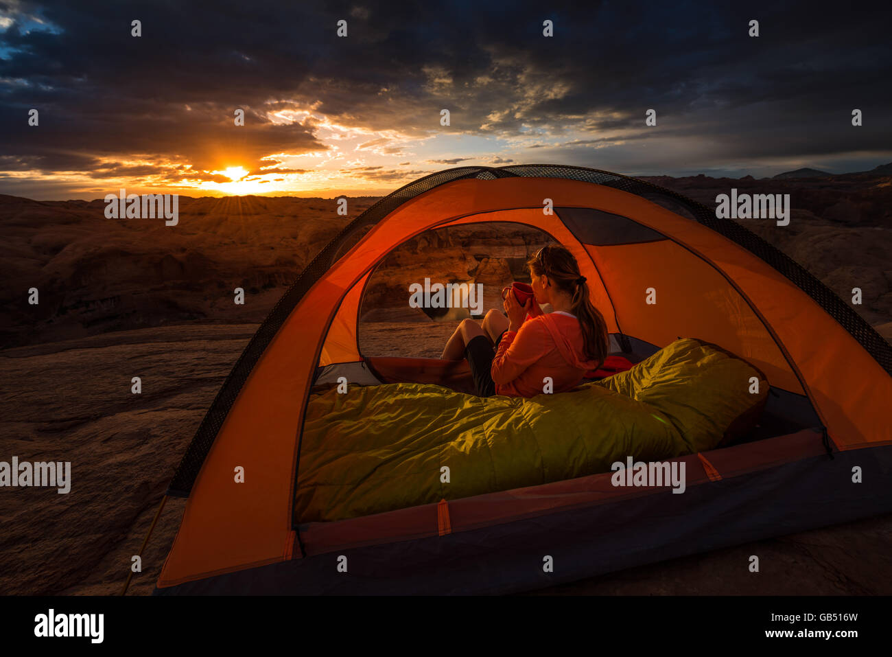 Frau, die Tasse Kaffee bei Sonnenaufgang Reflexion Canyon Camping Lake Powell Utah USA Stockfoto