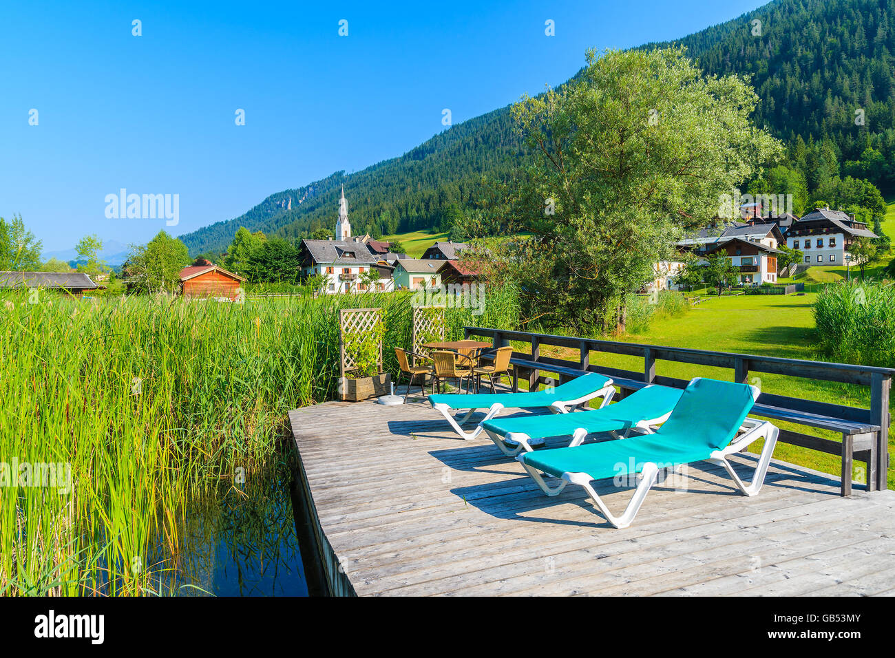 Liegestühle am Holzdeck am Ufer des Weissensee Bergsee im Sommerlandschaft der Alpen, Österreich Stockfoto