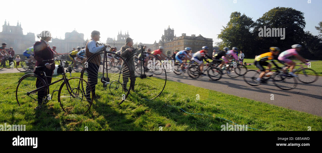 Rennfahrer beim Bike Blenheim Palace Event passieren Mitglieder des Benson Veteran Cycle Club (von links nach rechts) Sandra Catherall mit einem 1887 Peugeot solide müde Sicherheit, Grahame Catherall mit einem 1883 50 Zoll ordinary und Michael Coleman mit einem 1880 Bayliss - Thomson 48 Zoll ordinary. Stockfoto